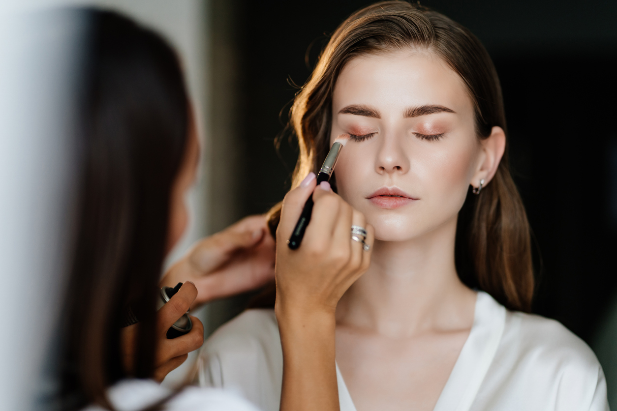 A beautiful young woman with long hair having makeup done