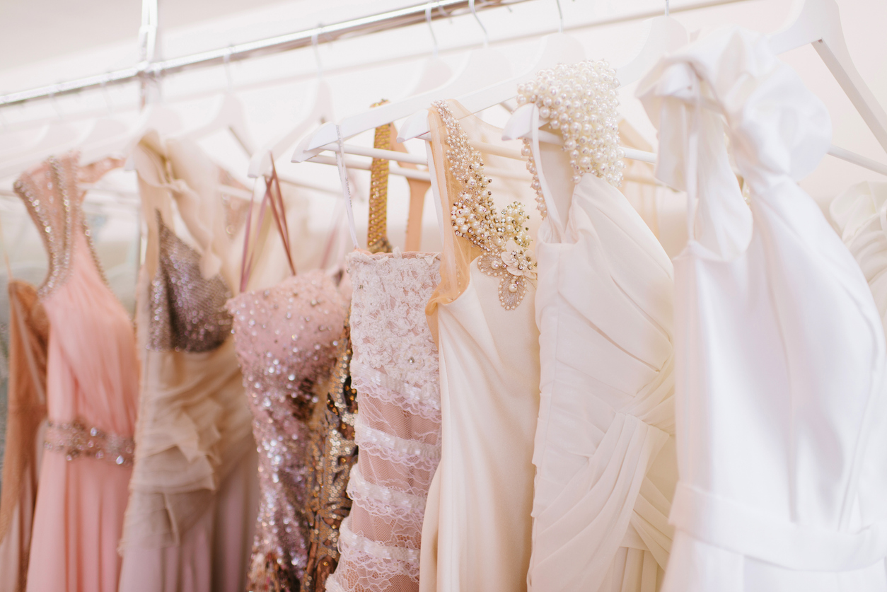 sparkly, formal dresses hanging on racks in woman’s wardrobe